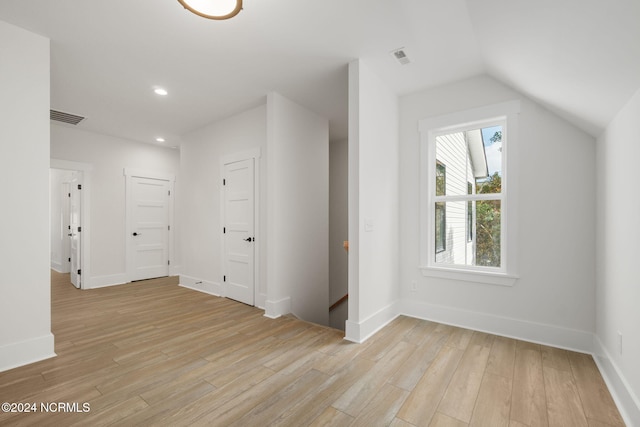 additional living space with light hardwood / wood-style flooring and vaulted ceiling