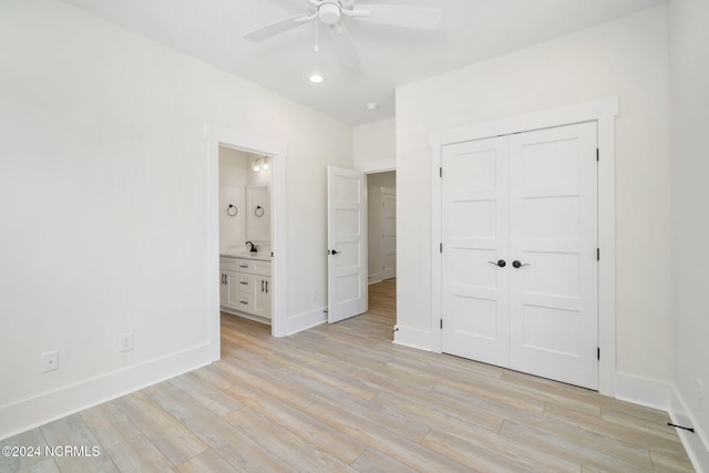 unfurnished bedroom with a closet, ensuite bath, ceiling fan, and light hardwood / wood-style flooring