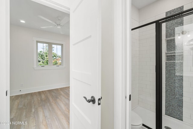 bathroom with a shower with door, toilet, ceiling fan, and hardwood / wood-style flooring