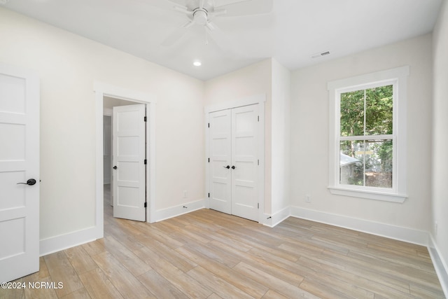 unfurnished bedroom featuring multiple windows, light wood-type flooring, a closet, and ceiling fan