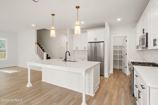 kitchen with a center island with sink, white cabinetry, sink, and appliances with stainless steel finishes