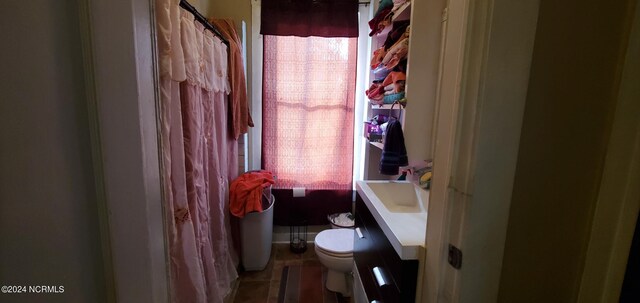 bathroom featuring tile patterned flooring, toilet, walk in shower, and vanity