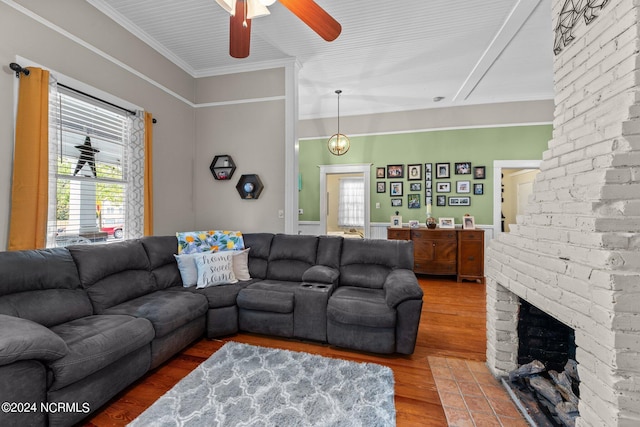 living area featuring a fireplace, a ceiling fan, ornamental molding, and wood finished floors