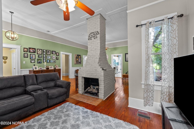 living area with crown molding, visible vents, ornate columns, wood-type flooring, and ceiling fan with notable chandelier