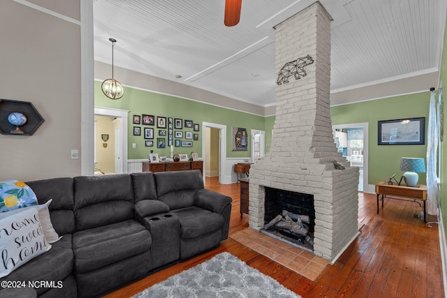 living room with ceiling fan, decorative columns, hardwood / wood-style flooring, a fireplace, and crown molding