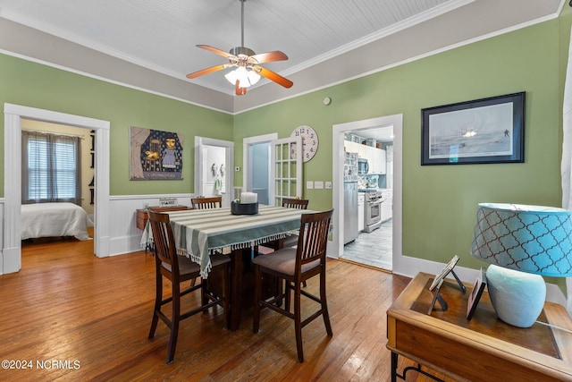 dining space featuring a ceiling fan, hardwood / wood-style floors, ornamental molding, and wainscoting