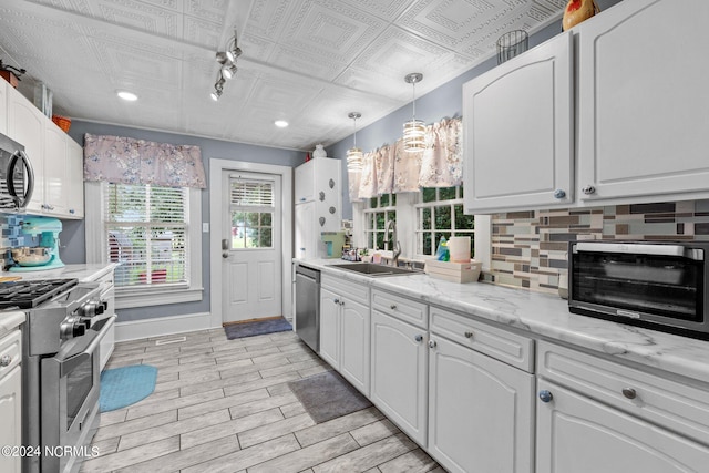 kitchen featuring hanging light fixtures, white cabinets, stainless steel appliances, light hardwood / wood-style flooring, and sink