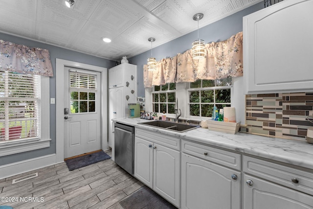 kitchen with hanging light fixtures, dishwasher, light hardwood / wood-style flooring, and white cabinets