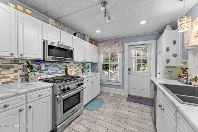 kitchen with light stone countertops, stainless steel appliances, and white cabinets