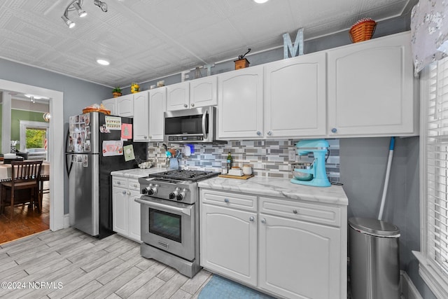 kitchen with light wood-style flooring, white cabinetry, appliances with stainless steel finishes, backsplash, and an ornate ceiling