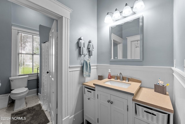 bathroom featuring vanity, wainscoting, curtained shower, and toilet