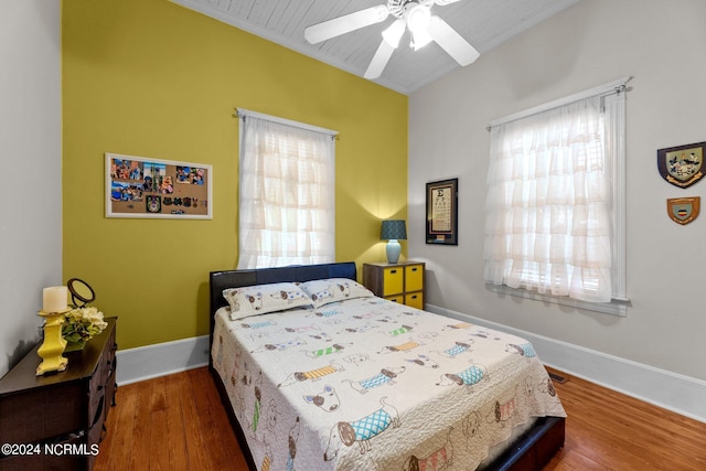 bedroom featuring baseboards, multiple windows, and wood finished floors