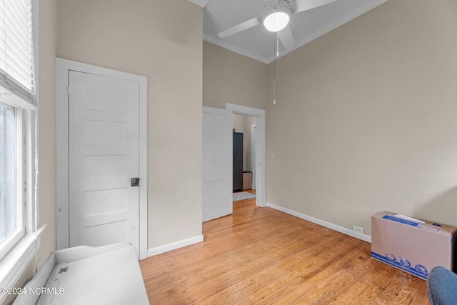 unfurnished bedroom with baseboards, ornamental molding, ceiling fan, high vaulted ceiling, and light wood finished floors