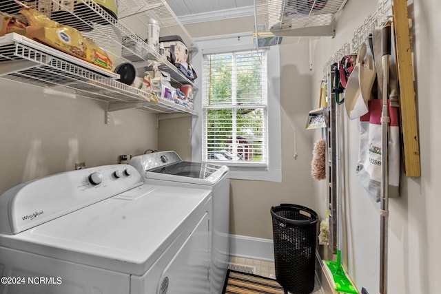 clothes washing area with ornamental molding, washer and clothes dryer, and a healthy amount of sunlight