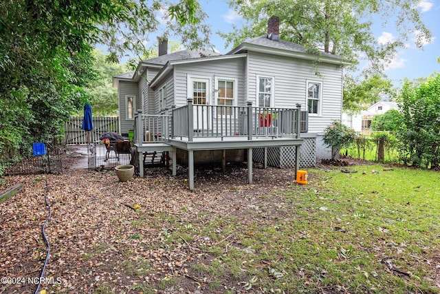 back of property featuring a patio, a chimney, a deck, fence, and a lawn