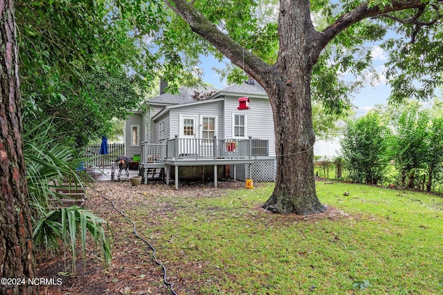 back of house with a wooden deck, a shingled roof, a lawn, and a chimney