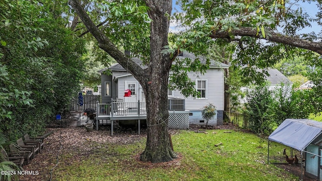 back of property featuring a deck, fence, a lawn, and crawl space
