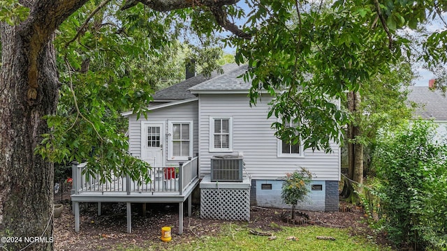 rear view of property with a deck, cooling unit, and roof with shingles