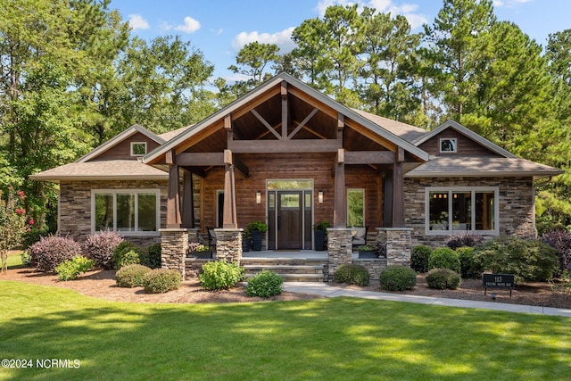 craftsman-style house featuring a porch, a front yard, and stone siding