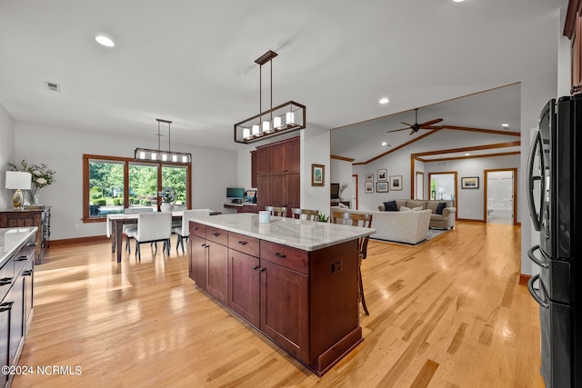 kitchen featuring a kitchen island, light stone countertops, light hardwood / wood-style floors, ceiling fan, and black fridge