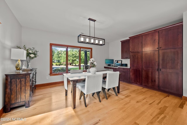 dining area featuring a chandelier, light wood-style flooring, and baseboards