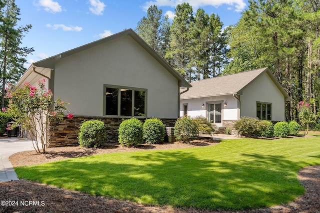 exterior space featuring stone siding, a yard, and stucco siding