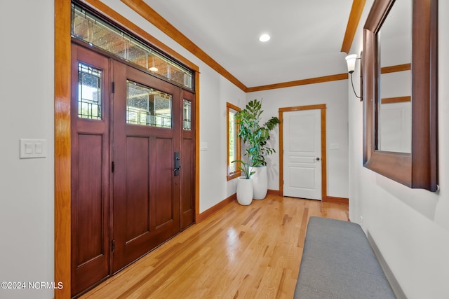 foyer with light wood-type flooring and ornamental molding