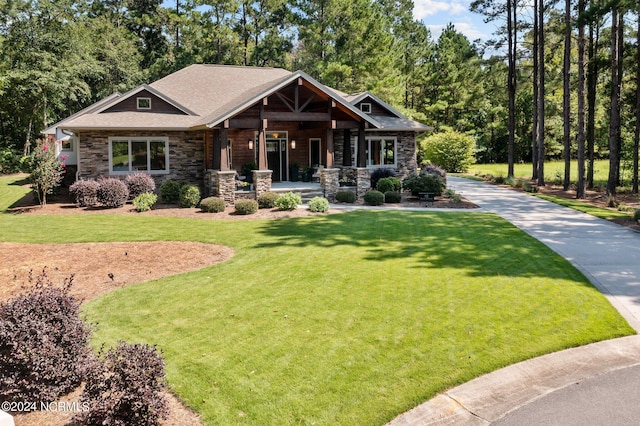 craftsman house featuring covered porch, stone siding, and a front lawn