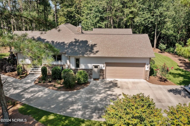 view of front of house featuring concrete driveway, stone siding, a chimney, an attached garage, and stucco siding