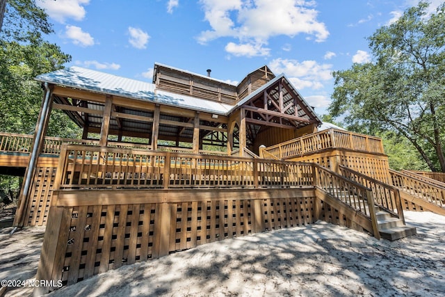 back of house featuring a deck, stairway, and metal roof