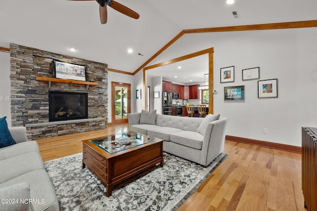 living room featuring ornamental molding, light hardwood / wood-style flooring, ceiling fan, a stone fireplace, and lofted ceiling