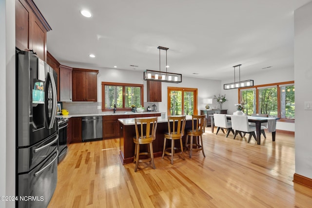 kitchen with light countertops, appliances with stainless steel finishes, a kitchen bar, and light wood-style flooring