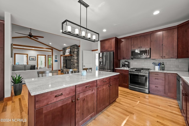 kitchen with lofted ceiling, backsplash, appliances with stainless steel finishes, open floor plan, and light wood-type flooring