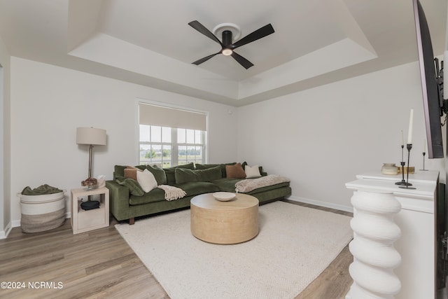 living room featuring ceiling fan, a raised ceiling, and light hardwood / wood-style floors