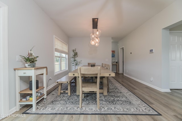 dining space featuring a chandelier, wood finished floors, and baseboards