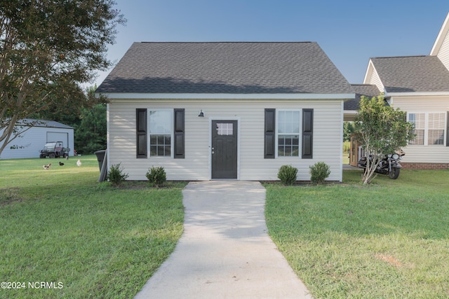 view of front facade with a shingled roof and a front yard