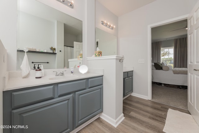 full bath featuring wood finished floors, connected bathroom, vanity, and baseboards