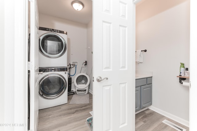 washroom featuring light wood-type flooring and stacked washer and clothes dryer