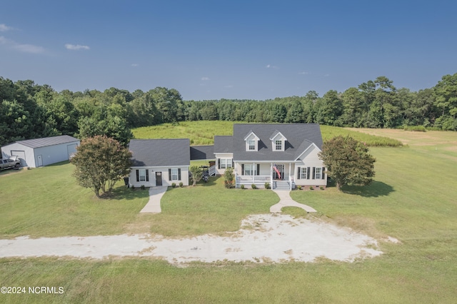 new england style home with a front yard and an outdoor structure