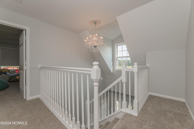 staircase featuring carpet, vaulted ceiling, and an inviting chandelier