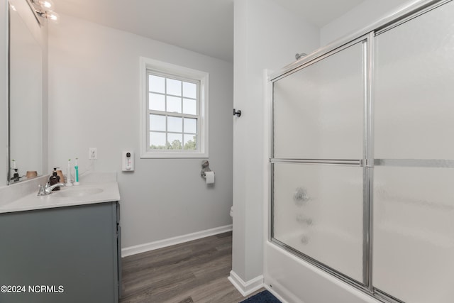 full bathroom featuring hardwood / wood-style floors, combined bath / shower with glass door, vanity, and toilet