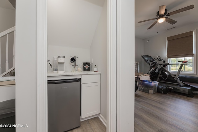 bar featuring ceiling fan, dishwashing machine, a bar, and light wood-type flooring