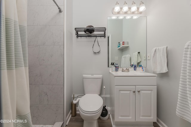 full bathroom featuring toilet, baseboards, a tile shower, and vanity