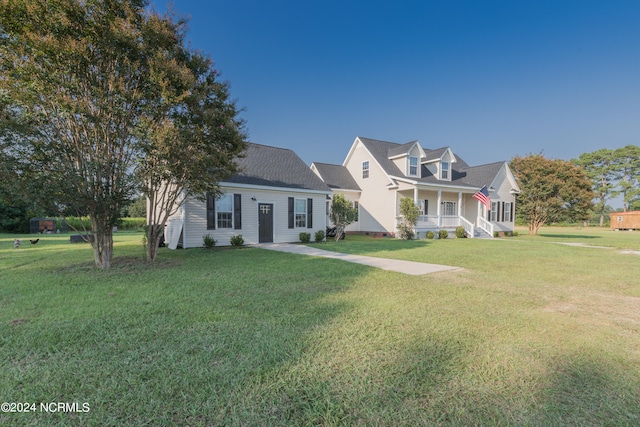 cape cod house with a front yard and covered porch