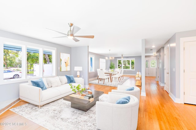 living room with ceiling fan with notable chandelier and wood-type flooring