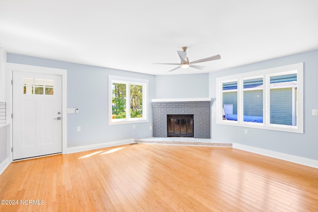 unfurnished living room featuring ceiling fan, light wood-type flooring, and a brick fireplace