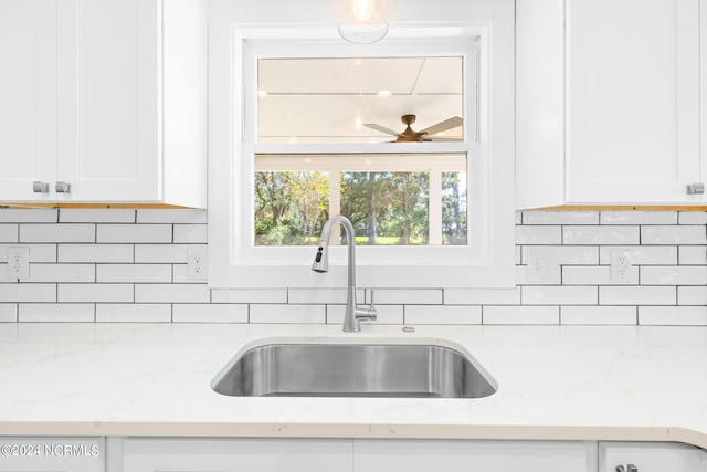 kitchen featuring sink, white cabinets, and light stone counters