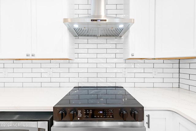 kitchen with tasteful backsplash, electric range, island range hood, and white cabinetry