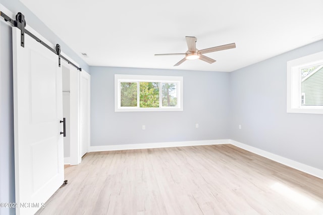 31 Augusta Dr, Oak Island, NC 28465 - unfurnished bedroom with a ceiling fan, light wood-style floors, a barn door, and baseboards