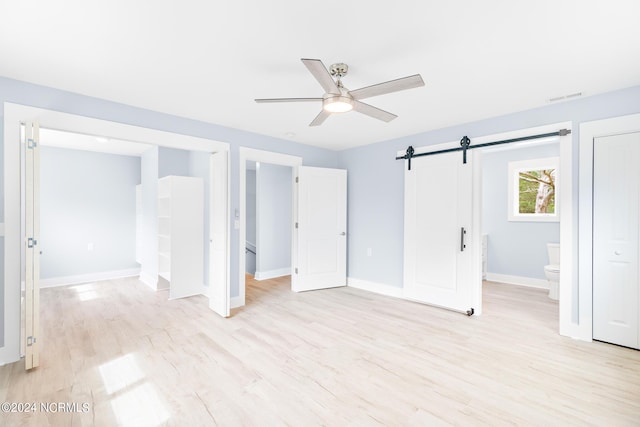 31 Augusta Dr, Oak Island, NC 28465 - unfurnished bedroom with light wood finished floors, a ceiling fan, visible vents, a barn door, and baseboards